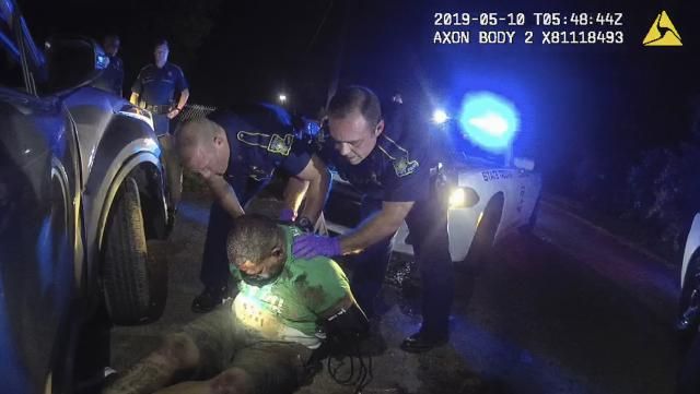 FILE - In this image from the body camera of Louisiana State Police Trooper Dakota DeMoss, his colleagues, Kory York, center left, and Chris Hollingsworth, center right, hold up Ronald Greene before paramedics arrived on May 10, 2019, outside of Monroe, La. An autopsy ordered by the FBI listed “prone restraint” among the other contributing factors in Greene’s violent death, including neck compression, physical struggle and cocaine use. (Louisiana State Police via AP, File)