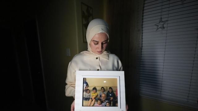 FILE - Maryam Kamalmaz hold a photo of her father with some of his 14 grandchildren in Grand Prairie, Texas, Jan. 17, 2024. U.S. officials have developed specific and highly credible intelligence suggesting that Majd Kamalmaz, an American citizen who disappeared seven years ago while traveling in Syria has died, Maryam Kamalmaz said Saturday, May 18. (AP Photo/Julio Cortez, File)