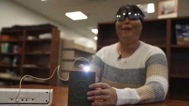 Minh Ha, assistive technology manager at the Perkins School for the Blind tries a LightSound device for the first time at the school's library in Watertown, Mass., on March 2, 2024. As eclipse watchers look to the skies in April 2024, new technology will allow people who are blind or visually impaired to hear and feel the celestial event. (AP Photo/Mary Conlon) Minh Ha, assistive technology manager at the Perkins School for the Blind tries a LightSound device for the first time at the school's library in Watertown, Mass., on March 2, 2024. As eclipse watchers look to the skies in April 2024, new technology will allow people who are blind or visually impaired to hear and feel the celestial event. (AP Photo/Mary Conlon)