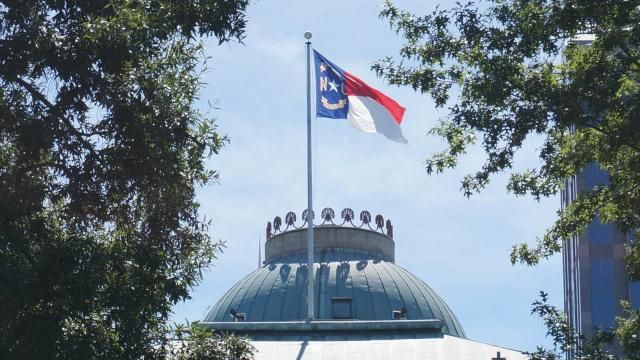 The North Carolina flag flies over the historic state capitol building.  