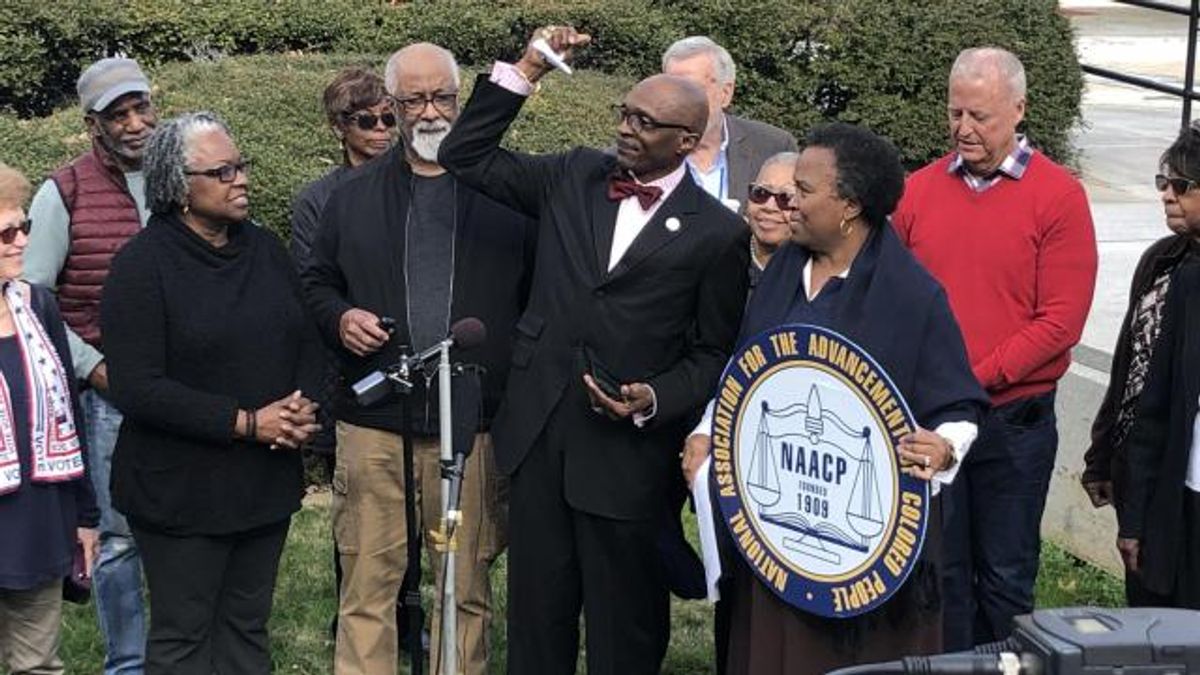 Rev. T. Anthony Spearman, president of the NC NAACP, balls up a voter ID explainer pamphlet at a Friday, Dec. 27, 2019, press conference on a court victory at least temporarily blocking photo ID at North Carolina's polls.