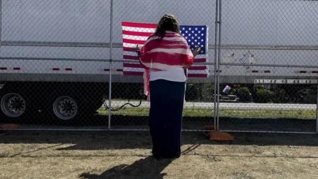 A woman prays as she faces a U.S. flag on the perimeter fence at the ReAwaken America Tour at Cornerstone Church in Batavia, N.Y., Sat., Aug. 13, 2022. (AP Photo/Carolyn Kaster) A woman prays as she faces a U.S. flag on the perimeter fence at the ReAwaken America Tour at Cornerstone Church in Batavia, N.Y., Sat., Aug. 13, 2022. (AP Photo/Carolyn Kaster)