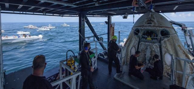 dozens of private vessels look on as crews recover the SpaceX Dragon Capsule