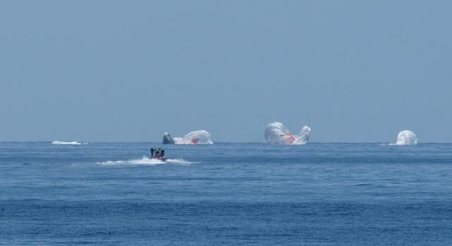 Recovery crews speed to the SpaceX Dragon capsule and four main chutes.