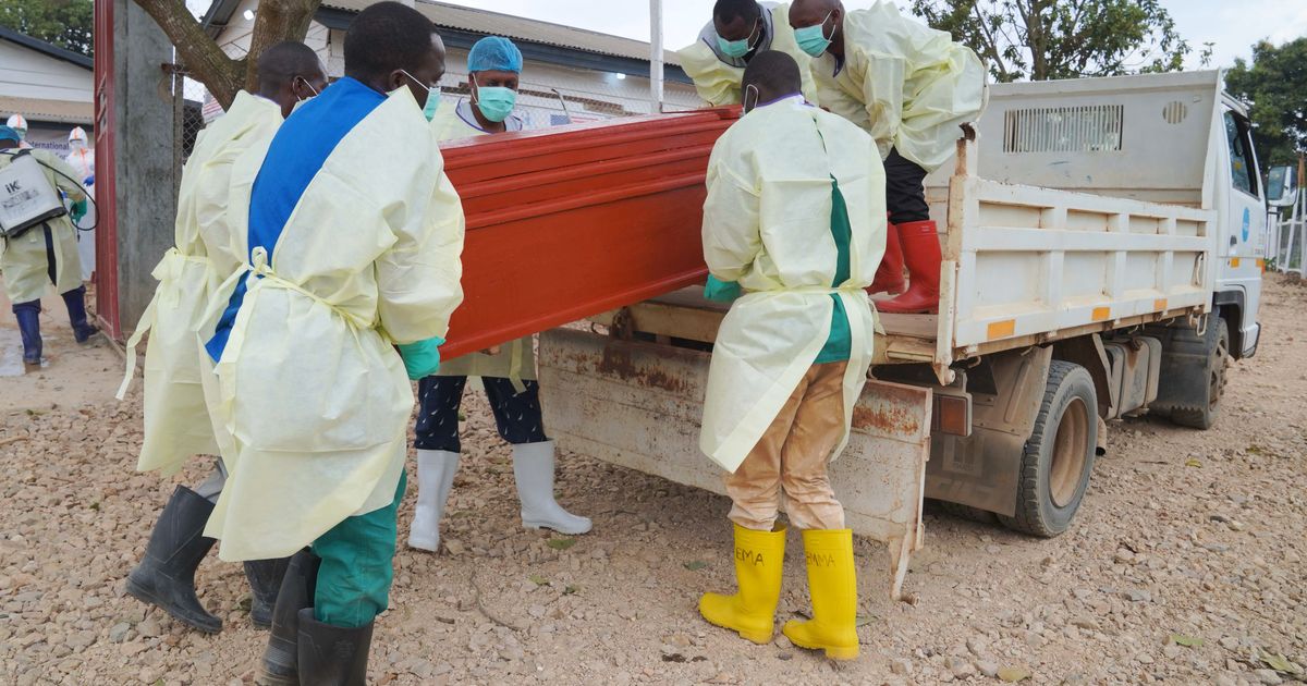 Health workers who are members of the safe and dignified burial team prepare to bury Abineno Justine, a 38 year old woman