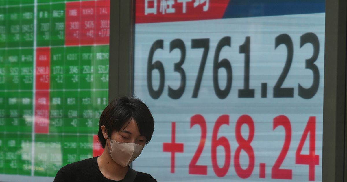 A person walks in front of an electronic stock board showing Japan's Nikkei index at a securities firm Tuesday, Sept. 15